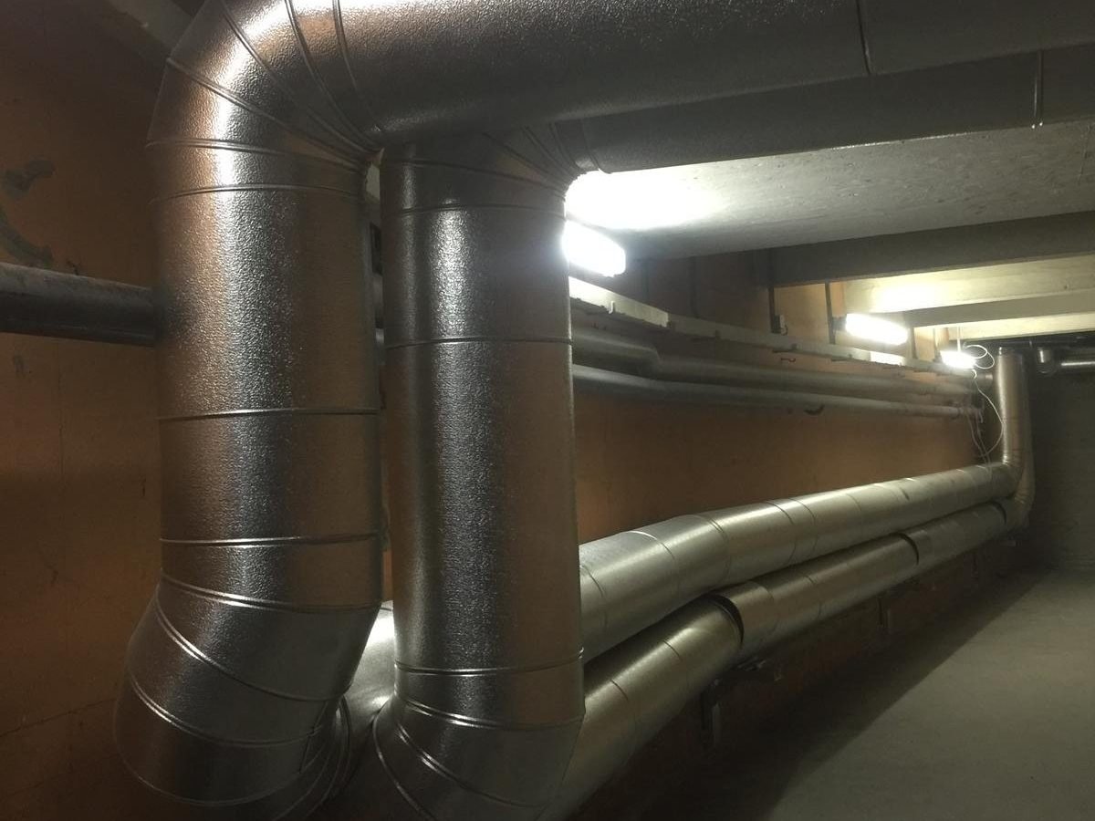 Isolierte Rohrleitungen mit Metallverkleidung und Bögen im Kellergang
